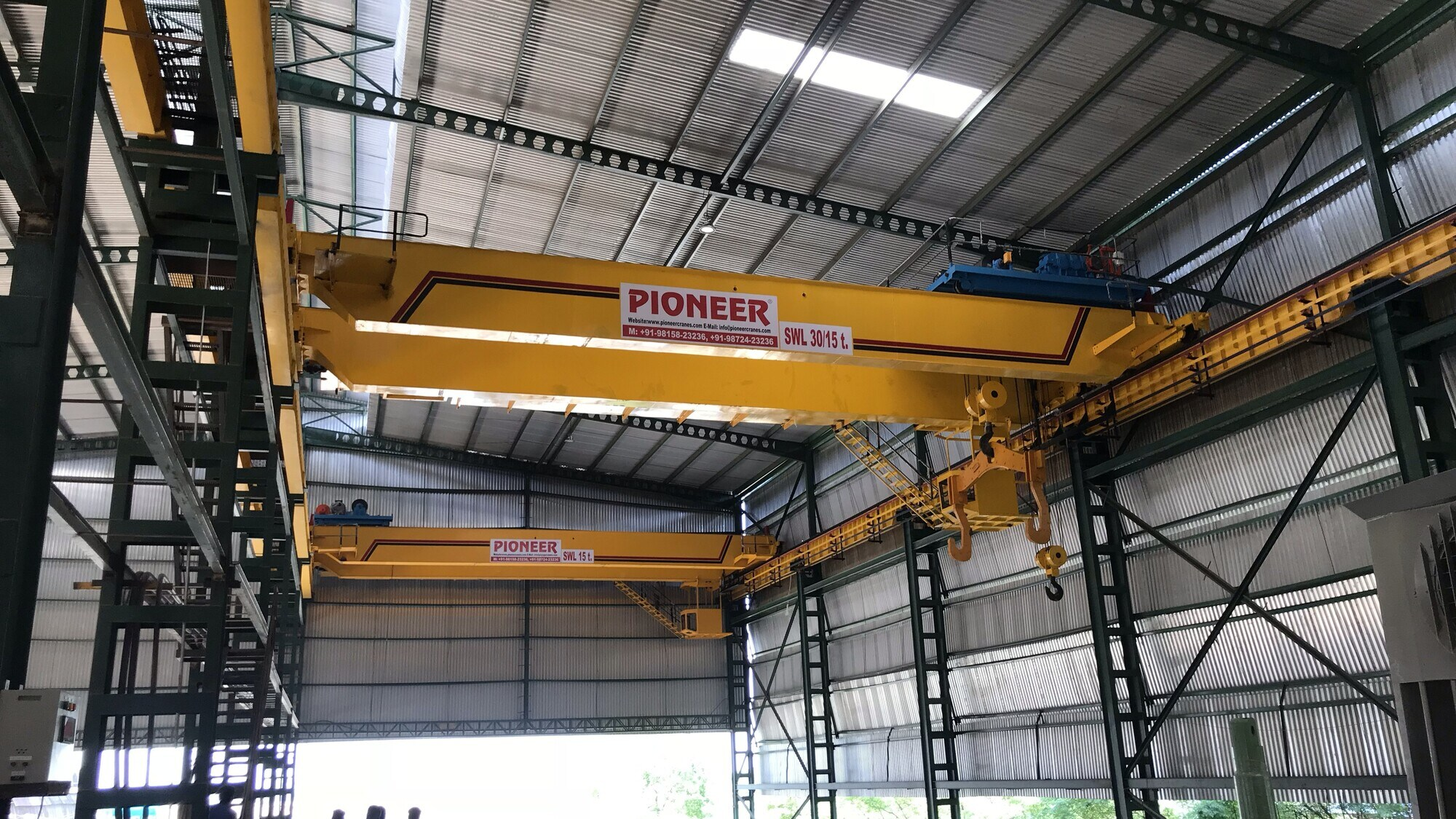 Yellow Pioneer overhead cranes spanning an industrial shed