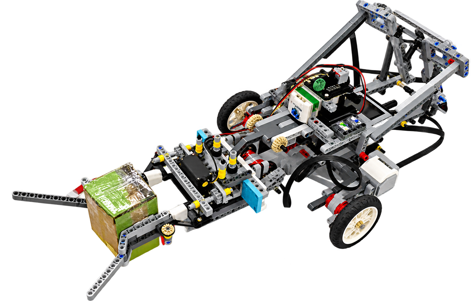 Photograph of the LEGO Technic rescue robot chassis with its controller, sensors, wheels and a front gripper holding a green cube